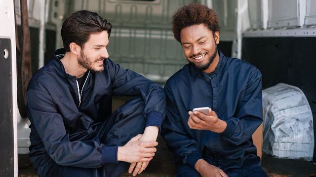 Twee lachende collega's kijken naar telefoon