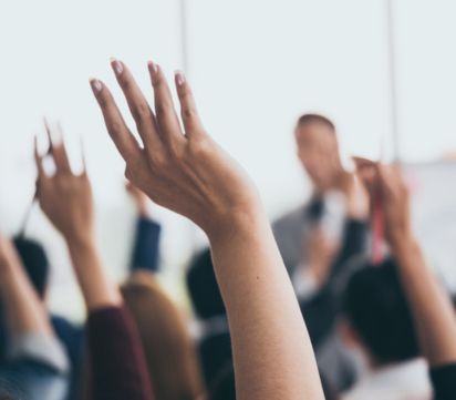 Mensen steken hun hand op tijdens een bijeenkomst