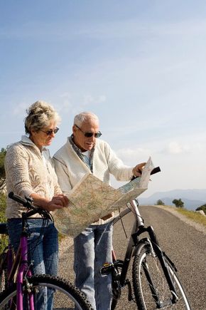 Een vrouw en een man staan naast hun fietsen en bekijken een routekaart.